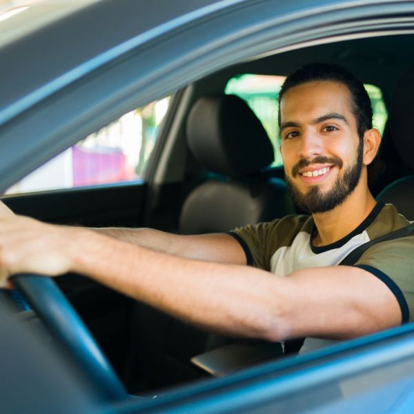 Motorista de aplicativo sorrindo dentro do carro