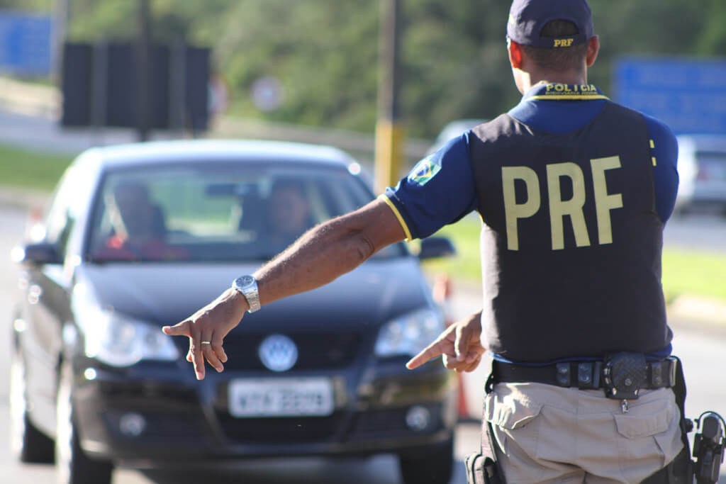 Policial rodoviário mandando carro parar.