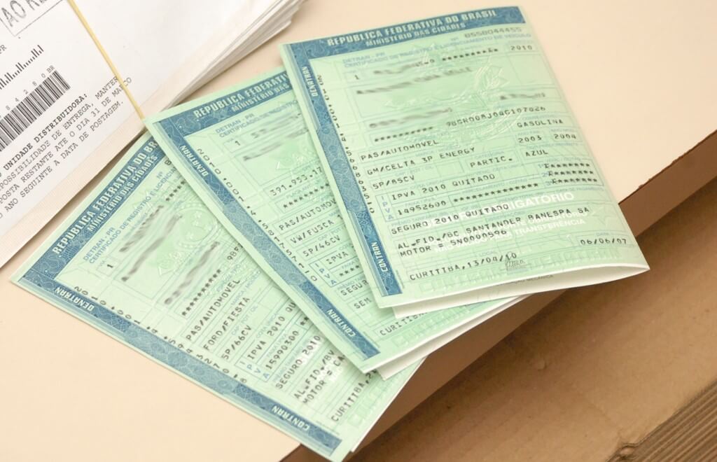 Saiba mais sobre Valor da transferência de veículo em 2023 (Preço Atualizado) Valor da transferência de véiculo - imagem de documentos do carro em cima de uma mesa
