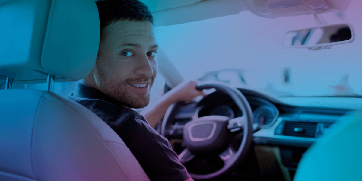 Telefone Azul Seguros - Na imagem um homem sentado no banco do motorista e com a mão no volante olha para trás e sorri.