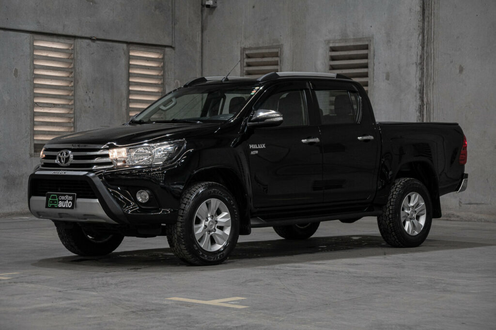 Foto de uma Hilux preta em uma garagem industrial