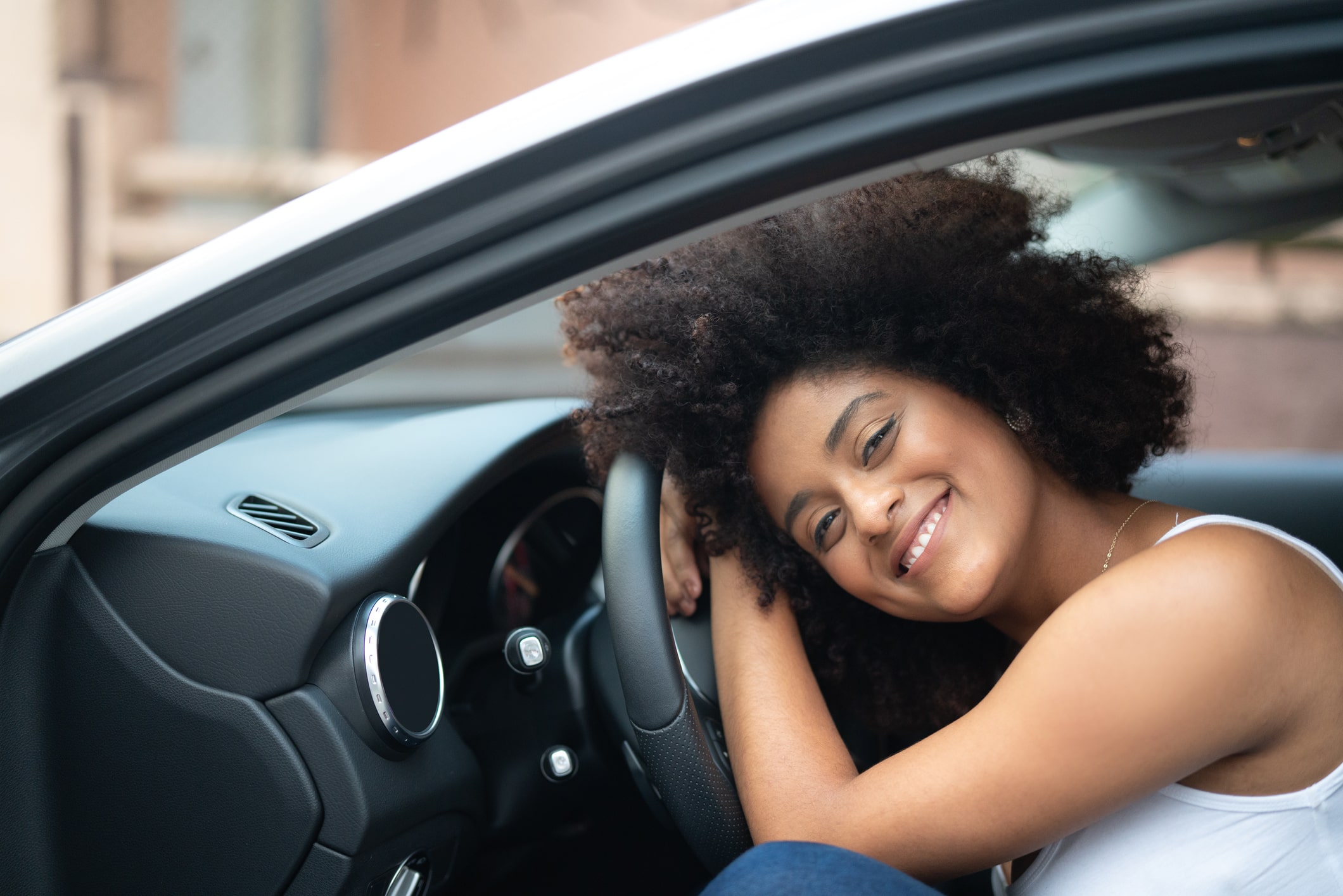 mulher negra sorrindo sobre volante de carro min Seguro auto para mulher é mais barato?