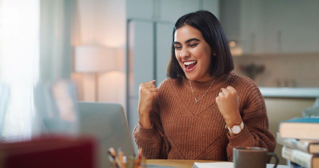 pessoal feliz sentada na mesa por ter passado no teste psicotécnico.